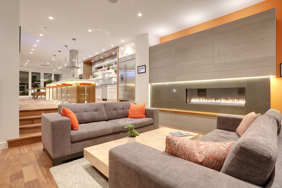 Modelo de salón para visitas abierto actual sin televisor con paredes blancas, suelo de madera en tonos medios y chimenea lineal