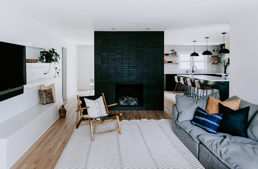 Inspiration pour un salon minimaliste avec parquet clair, une cheminée double-face et un manteau de cheminée en brique.