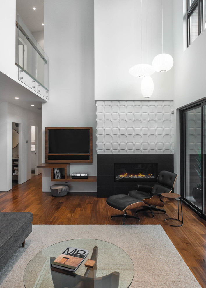 Living room - large 1960s loft-style medium tone wood floor and brown floor living room idea in Vancouver with white walls, a standard fireplace, a tile fireplace and a wall-mounted tv