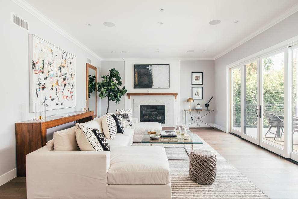 Example of a beach style medium tone wood floor and brown floor living room design in Los Angeles with gray walls and a standard fireplace