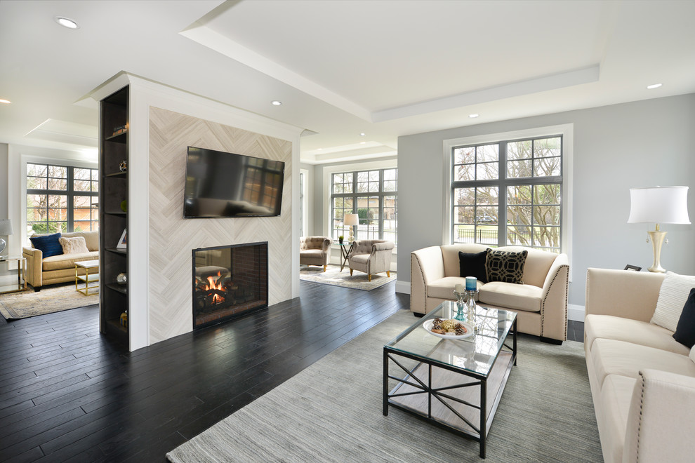 Inspiration for a medium sized traditional formal open plan living room in Chicago with grey walls, dark hardwood flooring, a two-sided fireplace, a tiled fireplace surround, a wall mounted tv and brown floors.