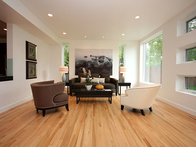 Modelo de salón abierto actual de tamaño medio sin televisor con paredes blancas y suelo de madera clara