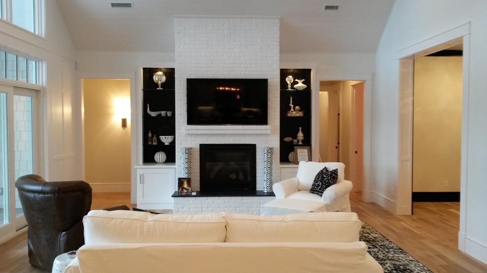 Großes, Abgetrenntes Modernes Wohnzimmer mit weißer Wandfarbe, hellem Holzboden, Kamin, Kaminumrandung aus Backstein und TV-Wand in Sonstige