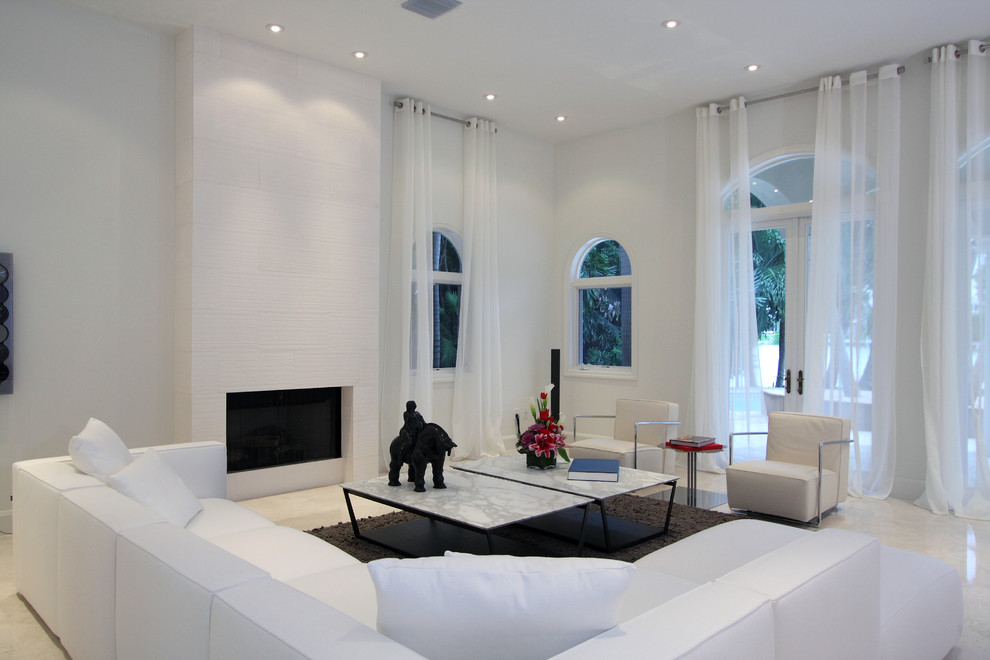 Пример оригинального дизайна: гостиная комната в современном стиле с белыми стенами, стандартным камином и мраморным полом