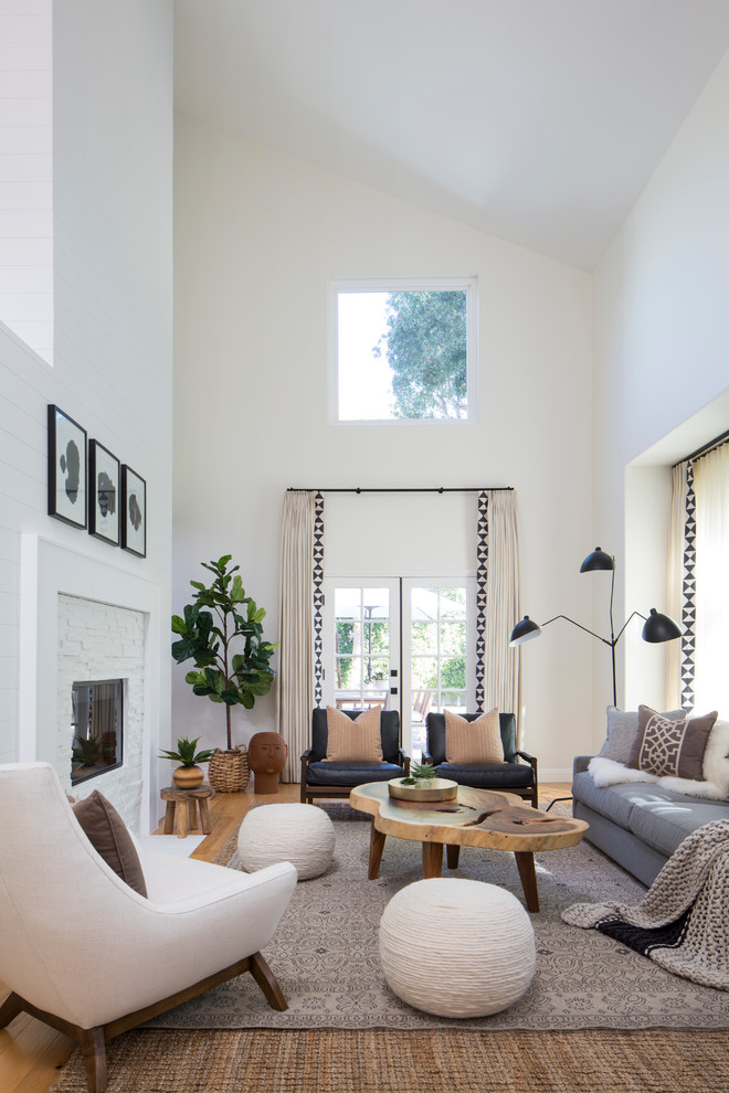 На фото: открытая гостиная комната среднего размера в стиле неоклассика (современная классика) с белыми стенами, светлым паркетным полом, двусторонним камином, фасадом камина из камня и коричневым полом без телевизора