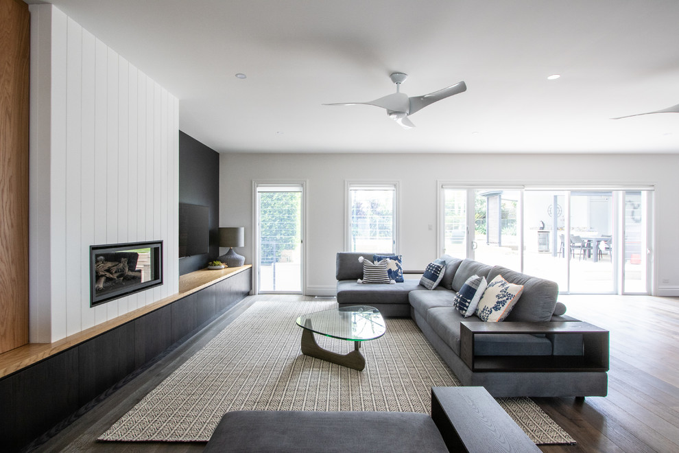 Offenes Modernes Wohnzimmer mit bunten Wänden, braunem Holzboden, Kamin, Kaminumrandung aus Holz und TV-Wand in Sydney
