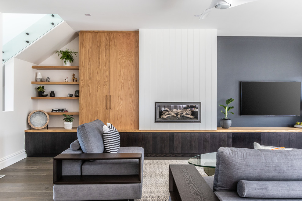 Diseño de salón abierto contemporáneo con paredes multicolor, suelo de madera en tonos medios, todas las chimeneas, marco de chimenea de madera y televisor colgado en la pared