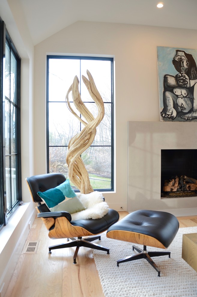Imagen de salón abierto minimalista grande con paredes grises, suelo de madera clara, todas las chimeneas, marco de chimenea de hormigón y suelo beige