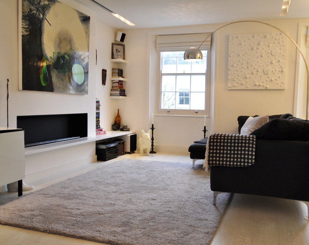 Réalisation d'un salon nordique de taille moyenne avec un mur blanc, une cheminée ribbon, parquet clair et canapé noir.