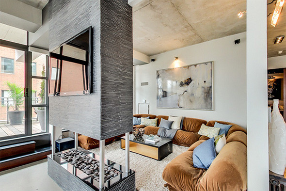 Large minimalist loft-style concrete floor and gray floor living room photo in Toronto with gray walls, a two-sided fireplace, a stone fireplace and a wall-mounted tv