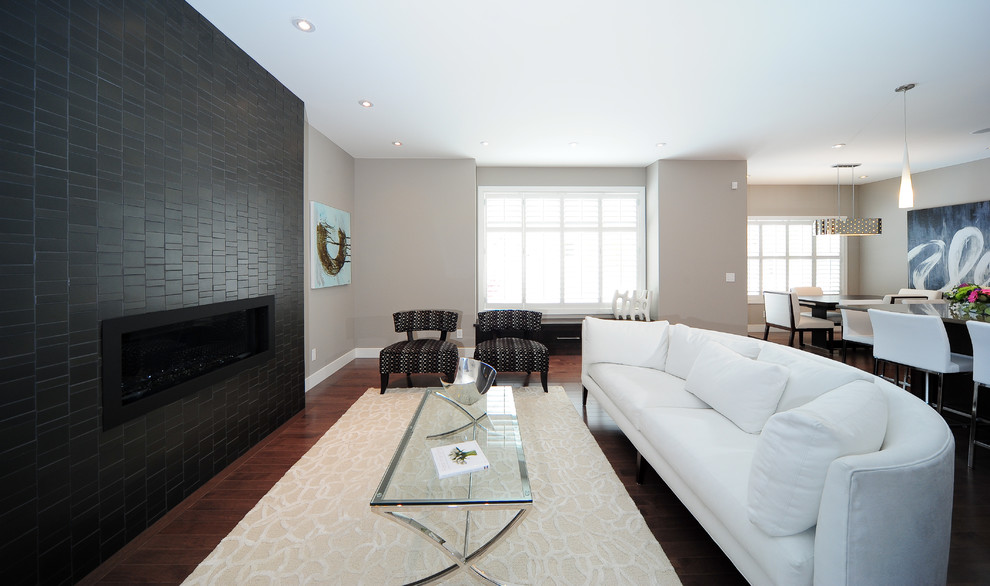 Modernes Wohnzimmer mit beiger Wandfarbe, dunklem Holzboden, Gaskamin und Kaminumrandung aus Stein in Calgary