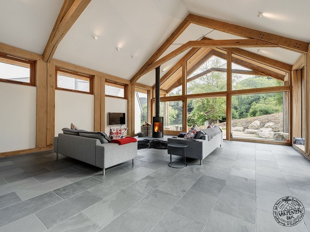 Offenes Modernes Wohnzimmer mit weißer Wandfarbe, Schieferboden, Eckkamin, Kaminumrandung aus Metall und TV-Wand in Devon