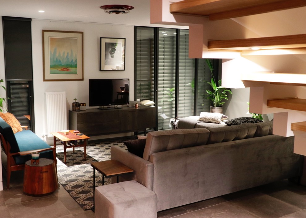 Источник вдохновения для домашнего уюта: открытая гостиная комната среднего размера в современном стиле с белыми стенами, полом из керамогранита, отдельно стоящим телевизором и серым полом