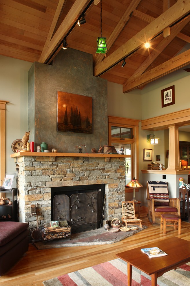 Inspiration pour un grand salon craftsman ouvert avec un mur vert, parquet clair, une cheminée standard et un manteau de cheminée en pierre.