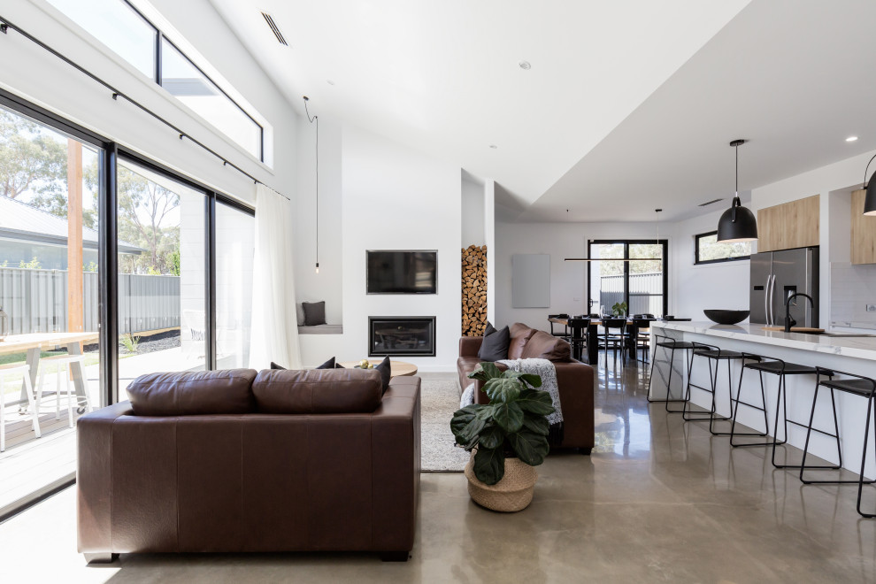 На фото: открытая гостиная комната среднего размера в стиле модернизм с белыми стенами, бетонным полом, стандартным камином, телевизором на стене и серым полом