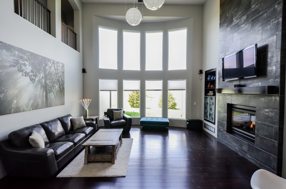 Diseño de salón abierto minimalista grande con paredes blancas, suelo de madera oscura, chimenea de doble cara, marco de chimenea de baldosas y/o azulejos y televisor colgado en la pared