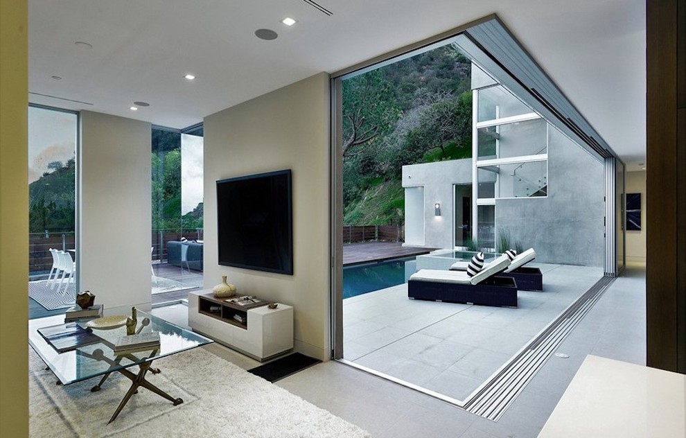 ロサンゼルスにある高級な中くらいなモダンスタイルのおしゃれなリビング (白い壁、コンクリートの床、横長型暖炉、金属の暖炉まわり、壁掛け型テレビ) の写真