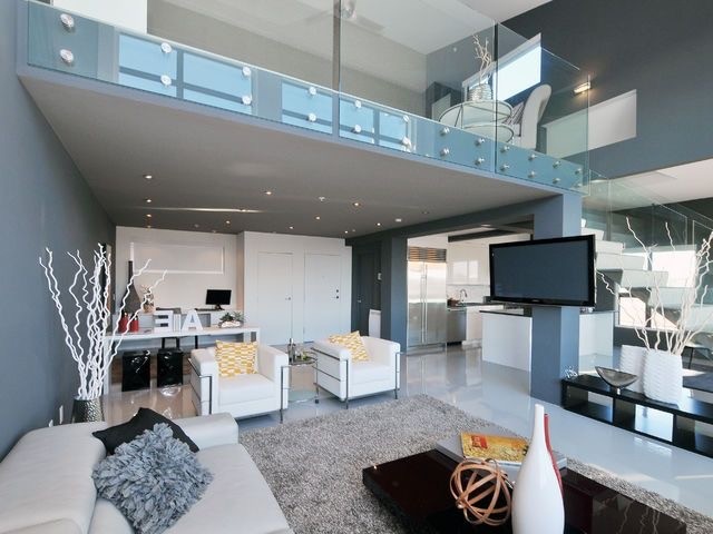 На фото: большая парадная, открытая гостиная комната в стиле модернизм с серыми стенами, бетонным полом и телевизором на стене