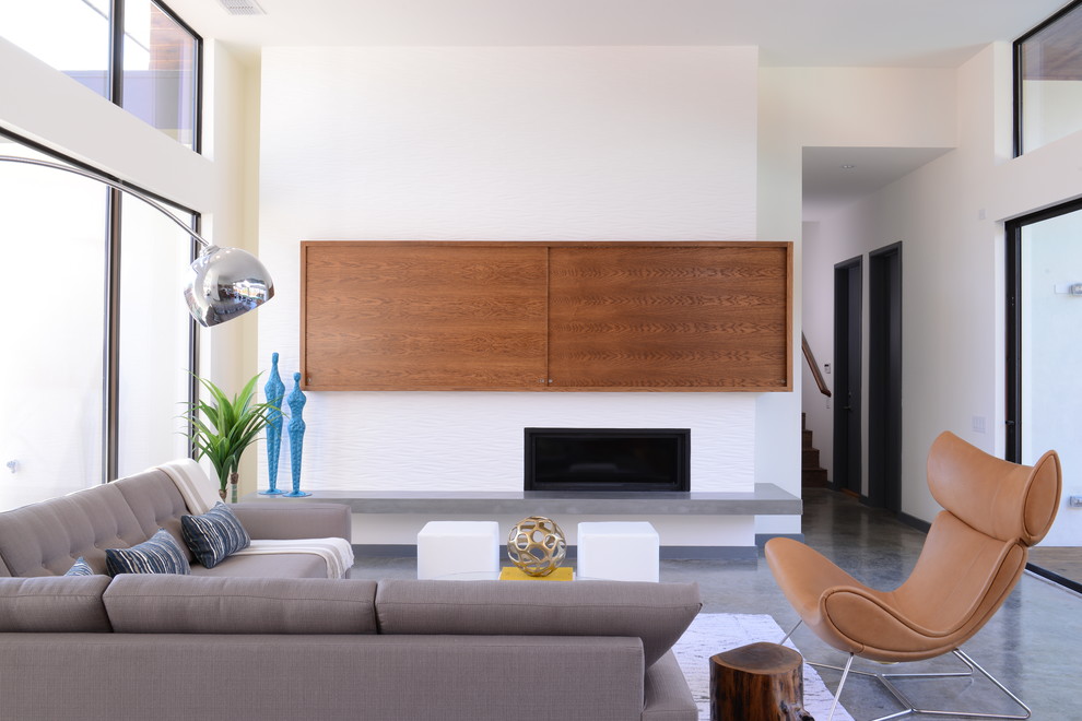 Exempel på ett mellanstort modernt allrum med öppen planlösning, med ett finrum, vita väggar, betonggolv, en bred öppen spis, en dold TV och en spiselkrans i trä