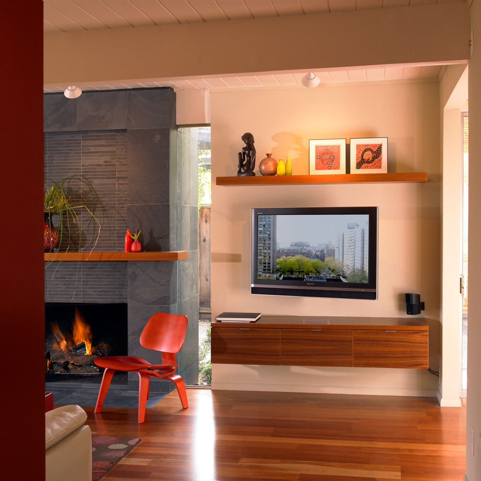 Cette image montre un salon bohème avec un mur beige et un téléviseur fixé au mur.