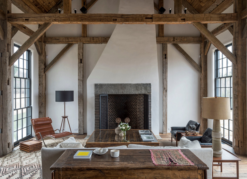 Cette image montre un grand salon traditionnel ouvert avec un mur blanc, un sol en bois brun, une cheminée standard, un manteau de cheminée en brique, aucun téléviseur et éclairage.