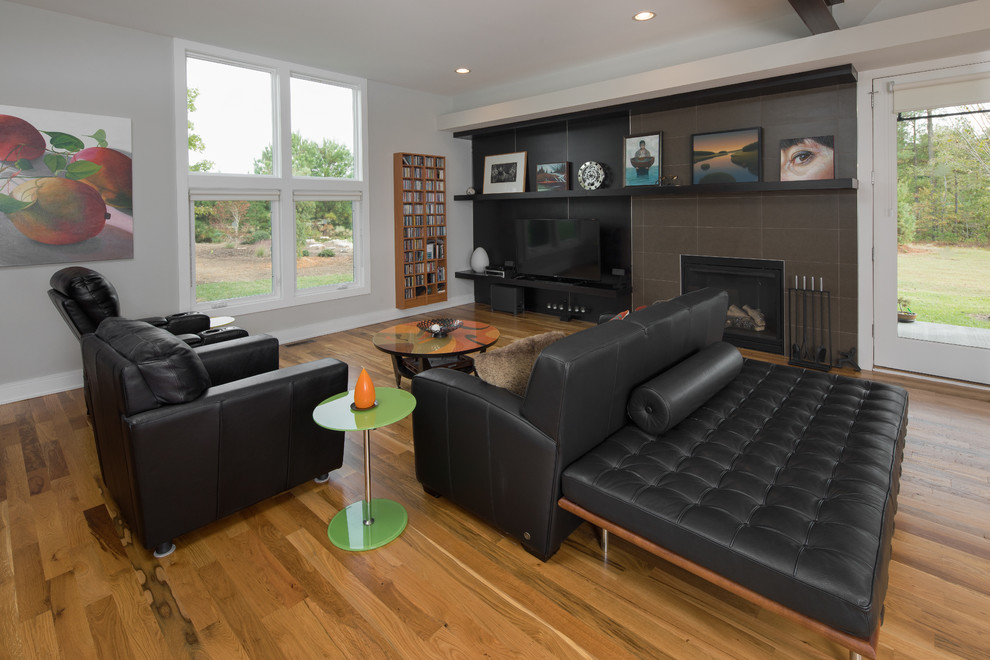 Пример оригинального дизайна: открытая гостиная комната среднего размера в стиле модернизм с серыми стенами, светлым паркетным полом, стандартным камином, фасадом камина из плитки и телевизором на стене
