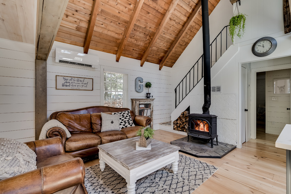 Diseño de salón para visitas abierto campestre sin televisor con paredes blancas, suelo de madera clara, estufa de leña y suelo beige
