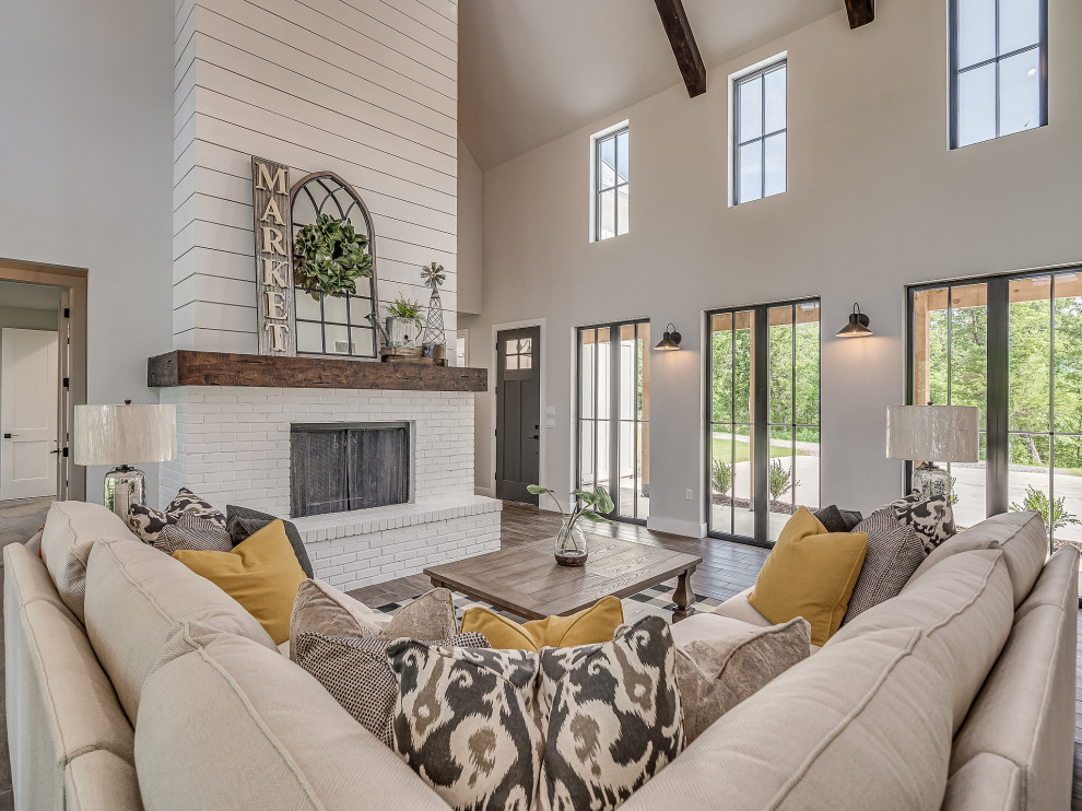 Inspiration for a large country open plan living room in Other with ceramic flooring, a standard fireplace, a brick fireplace surround, brown floors, a vaulted ceiling and tongue and groove walls.