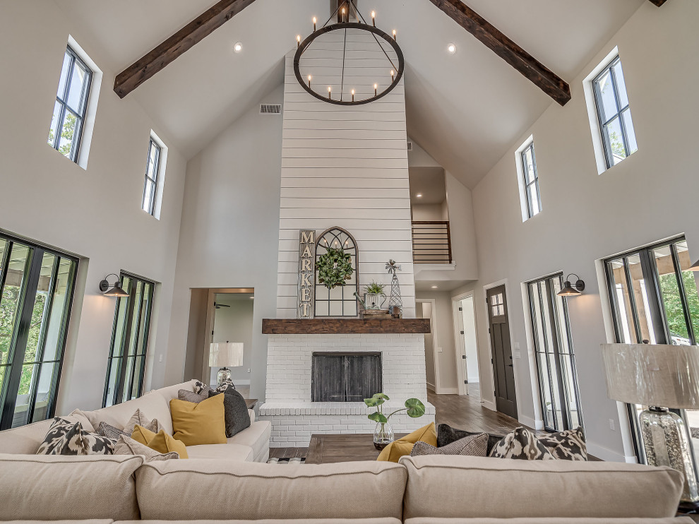 Large country open concept ceramic tile, brown floor, vaulted ceiling and shiplap wall living room photo with a standard fireplace and a brick fireplace