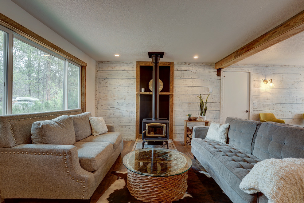 Foto di un soggiorno rustico di medie dimensioni e aperto con pareti bianche, pavimento in laminato, stufa a legna, cornice del camino in pietra e pavimento marrone
