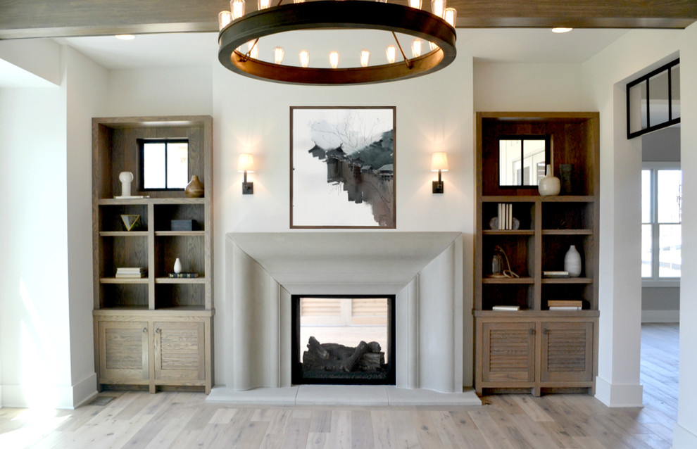 Modelo de salón para visitas abierto de estilo de casa de campo grande con paredes blancas, suelo de madera en tonos medios, chimenea de doble cara y marco de chimenea de hormigón