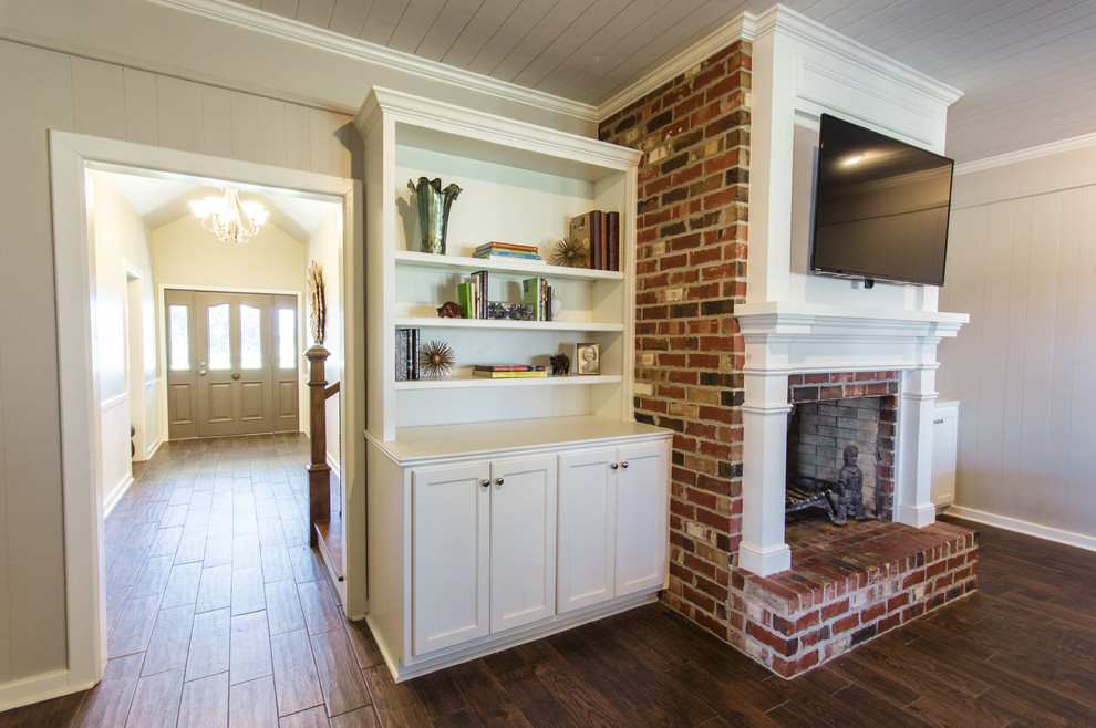 Photo of a medium sized rural formal open plan living room in New Orleans with beige walls, medium hardwood flooring, a standard fireplace, a brick fireplace surround and a wall mounted tv.