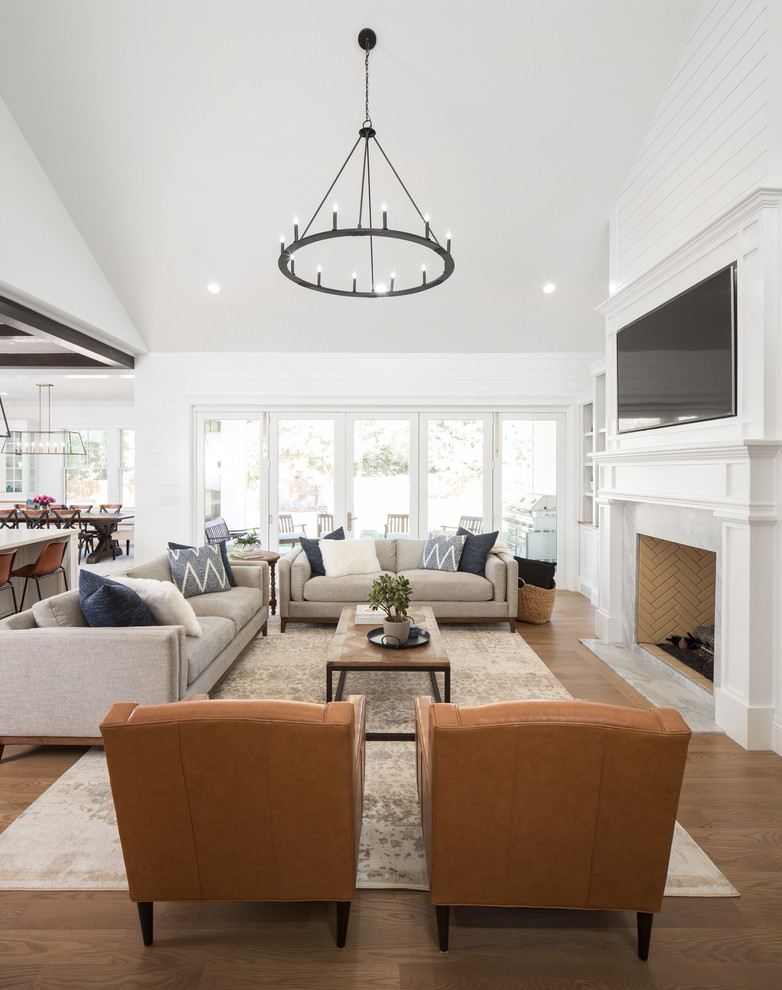 Example of a cottage open concept medium tone wood floor and brown floor living room design in Salt Lake City with white walls, a standard fireplace, a stone fireplace and a wall-mounted tv