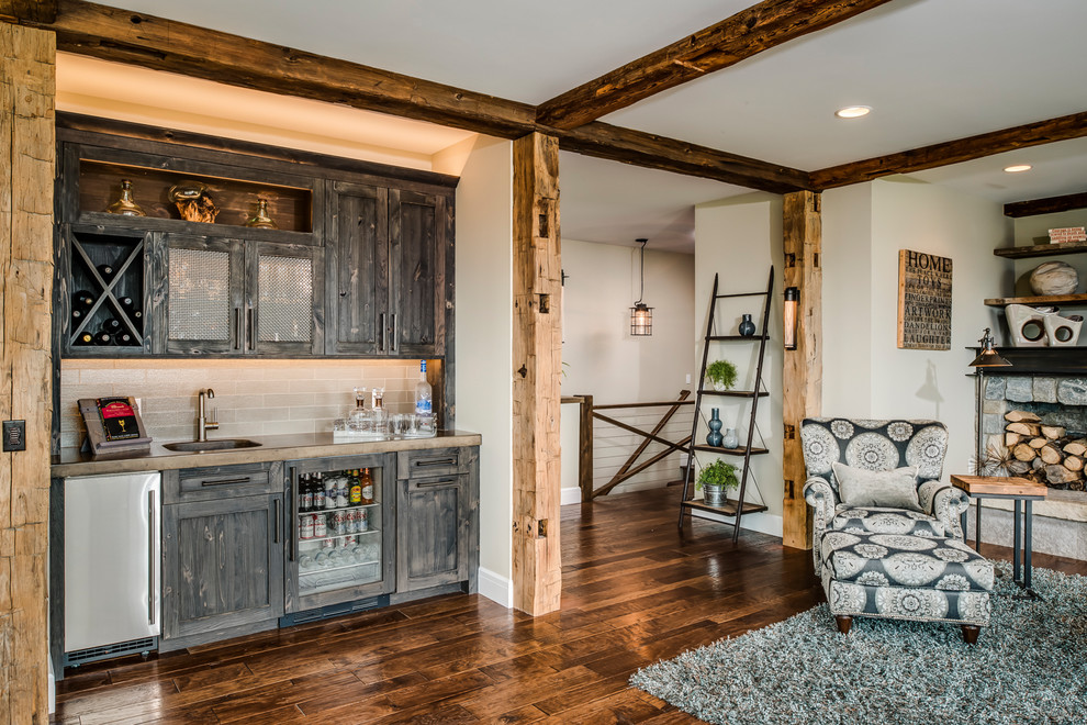 Photo of a farmhouse open plan living room in Other with a home bar, beige walls, dark hardwood flooring, a standard fireplace, a stone fireplace surround, a built-in media unit and brown floors.