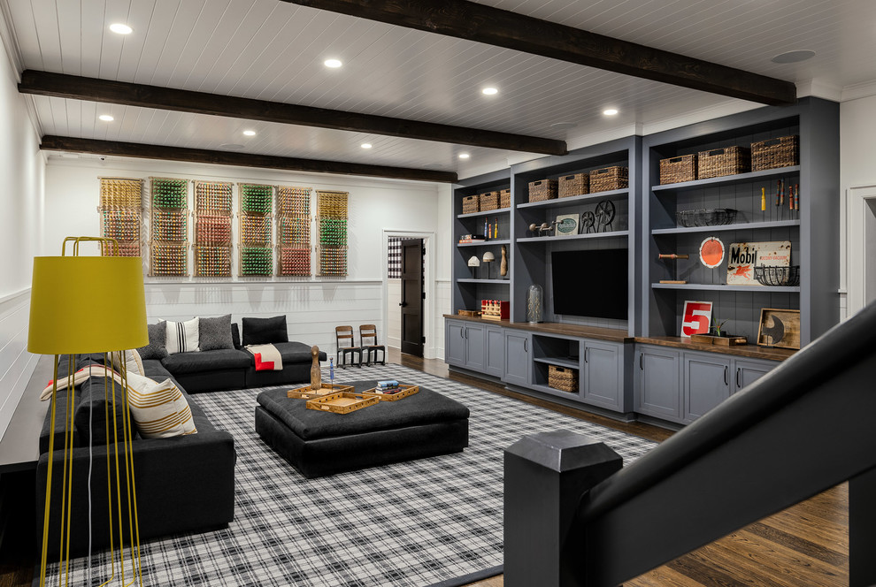 Modelo de salón para visitas abierto de estilo de casa de campo grande con paredes blancas, suelo de madera oscura, televisor colgado en la pared y suelo marrón