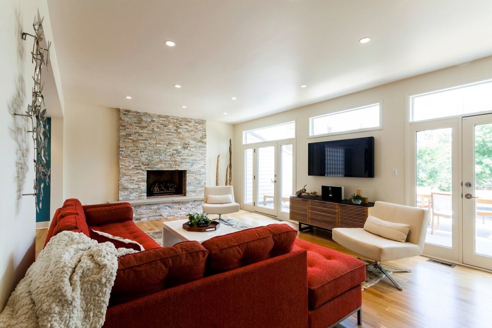 Foto di un grande soggiorno moderno aperto con pareti bianche, pavimento in legno massello medio, cornice del camino in pietra, camino classico e TV a parete