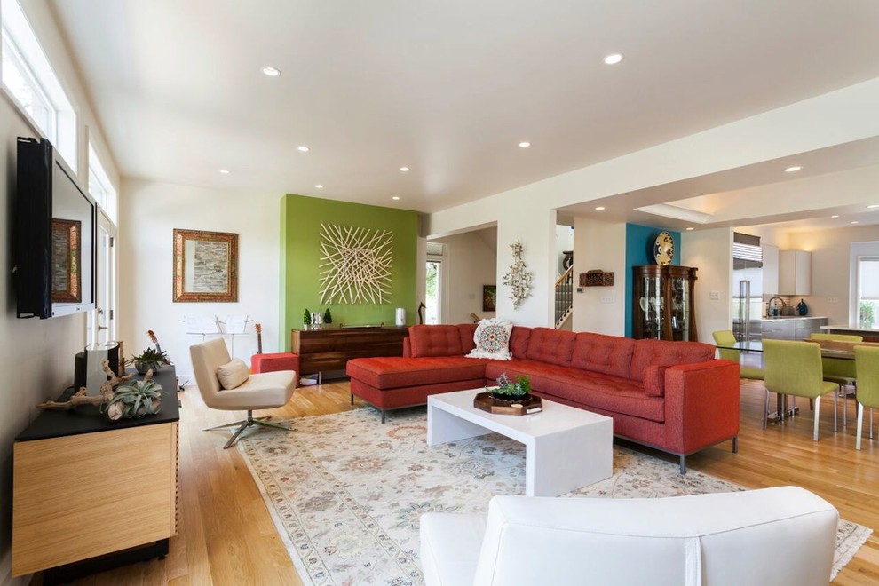 Immagine di un grande soggiorno minimalista aperto con pareti verdi, parquet chiaro, nessun camino e TV a parete