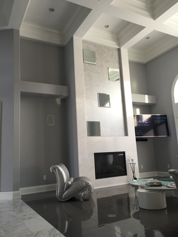 Cette image montre un grand salon minimaliste fermé avec un mur gris, un sol en carrelage de céramique, une cheminée standard, un manteau de cheminée en carrelage et un téléviseur fixé au mur.