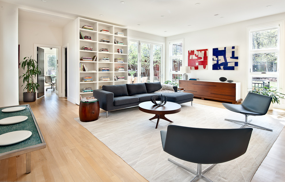 Example of a large minimalist open concept light wood floor living room design in Los Angeles with white walls and a media wall