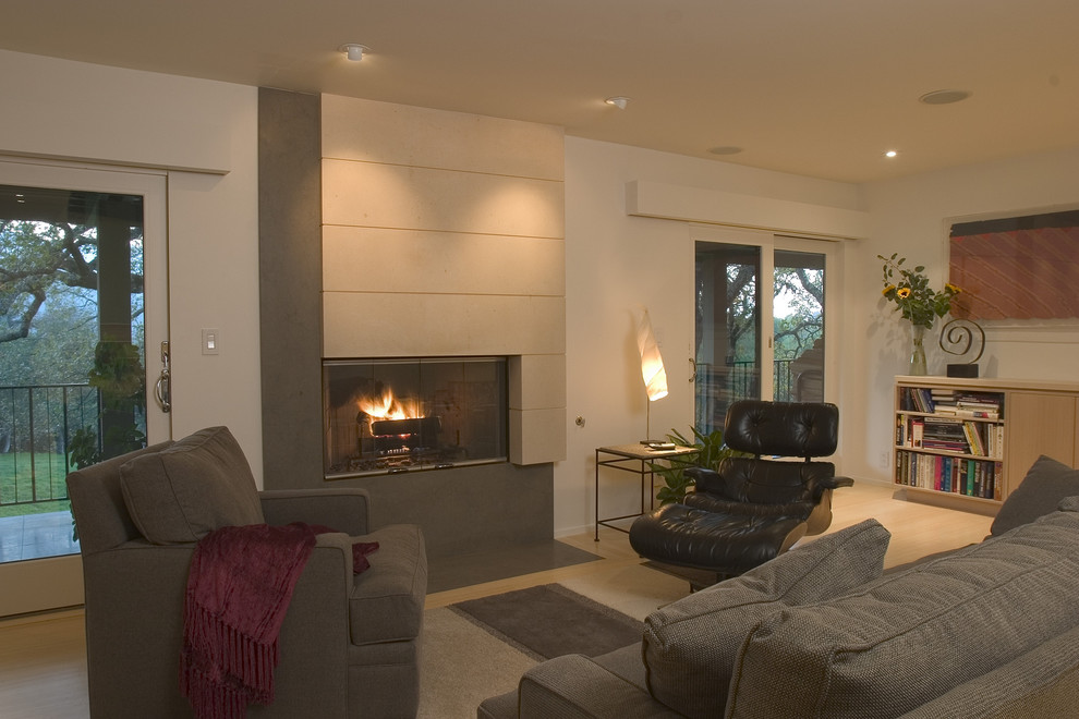 Example of a large minimalist formal and open concept light wood floor and beige floor living room design in San Francisco with beige walls, a standard fireplace, a concrete fireplace and no tv