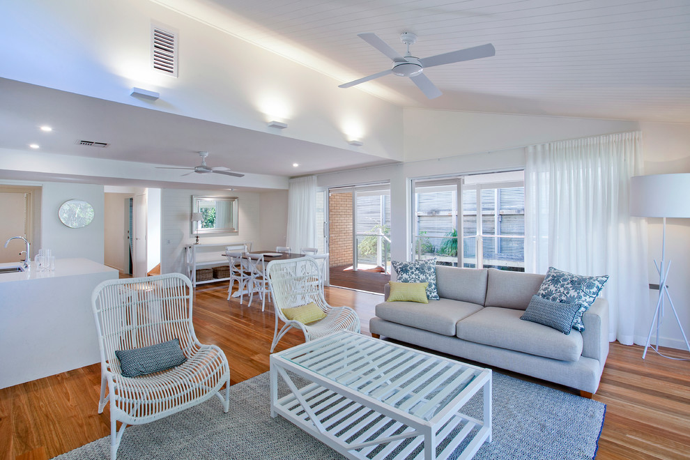 Medium sized coastal open plan living room in Sunshine Coast with white walls, medium hardwood flooring and a freestanding tv.