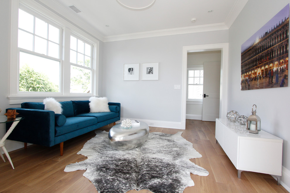 Photo of a small modern enclosed living room in New York with a reading nook, grey walls and light hardwood flooring.