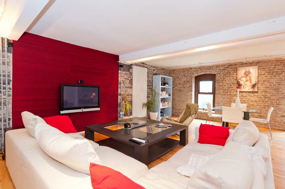 Modelo de salón abierto bohemio grande con paredes multicolor, suelo de madera clara y televisor colgado en la pared