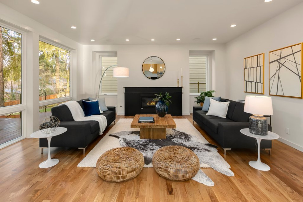 Large modern open plan living room in Seattle with white walls, medium hardwood flooring, a standard fireplace and brown floors.