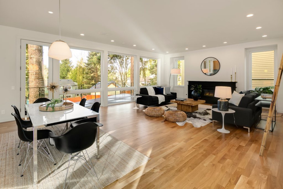 Immagine di un grande soggiorno minimalista aperto con pareti bianche, pavimento in legno massello medio, camino classico e pavimento marrone