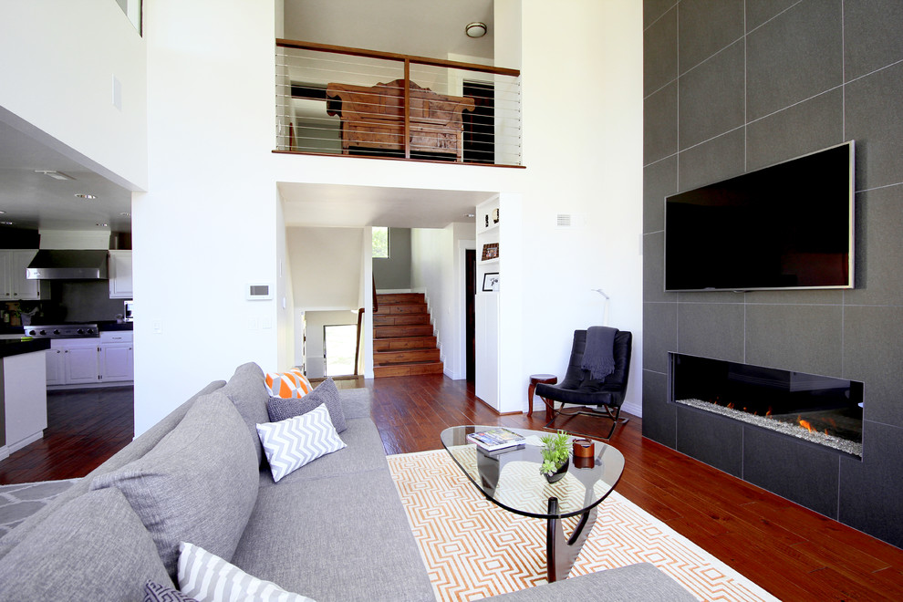 Idee per un soggiorno minimalista stile loft con pareti bianche, pavimento in legno massello medio, camino lineare Ribbon e cornice del camino piastrellata