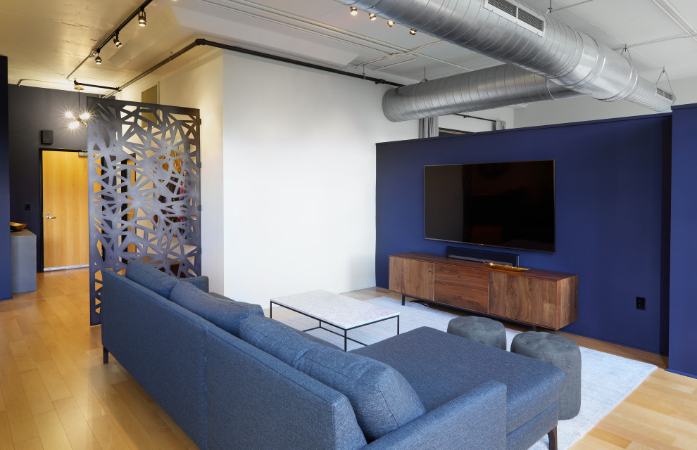 Immagine di un soggiorno moderno di medie dimensioni e stile loft con pareti blu, parquet chiaro, nessun camino e TV a parete