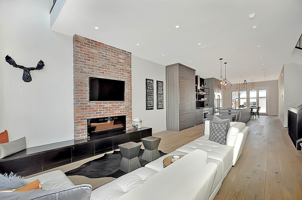 Offenes Industrial Wohnzimmer mit grauer Wandfarbe, hellem Holzboden, Hängekamin, Kaminumrandung aus Backstein und TV-Wand in Calgary