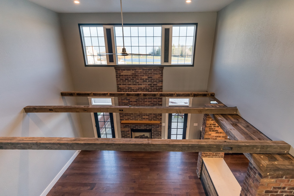 Large industrial formal open plan living room in Chicago with grey walls, medium hardwood flooring, a standard fireplace, a brick fireplace surround and no tv.