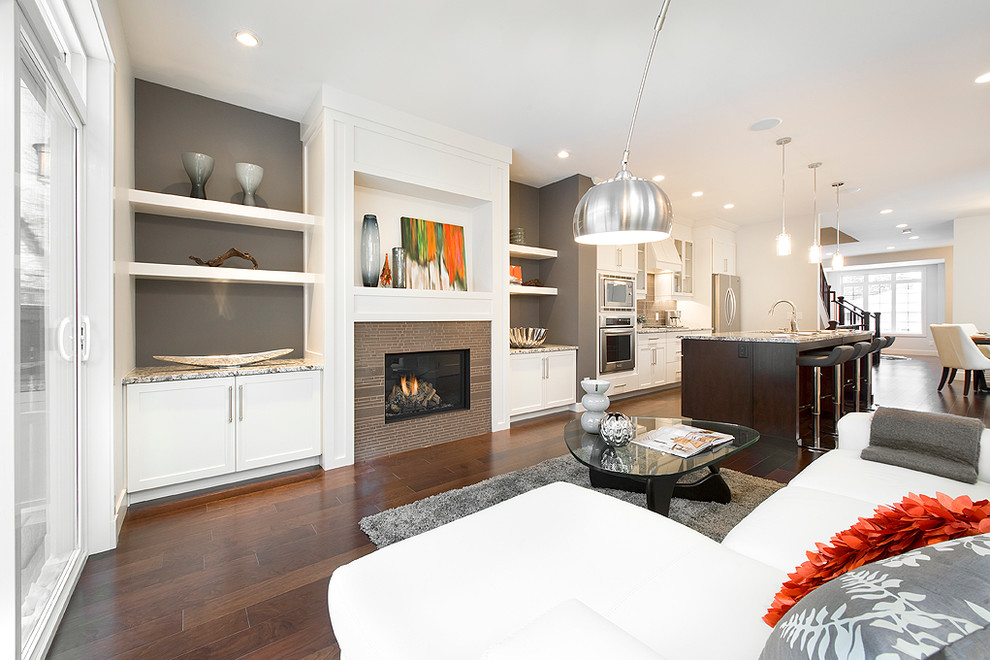 This is an example of a contemporary open plan living room in Calgary with white walls, dark hardwood flooring and a standard fireplace.